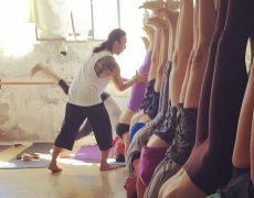 Eddy Toyonaga correcting students in a group arm balance yoga workshop