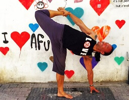Eddy Toyonaga performing a yoga pose in Tel Aviv in front of graffiti