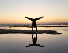 Eddy Toyonaga doing a handstand at the beach in sunset