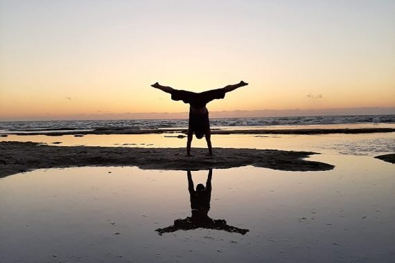 Eddy Toyonaga doing a handstand at the beach in sunset